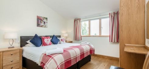 As part of Silver Mist holiday cottage which sleeps 16, Bedroom 3 in Early Mist is prettily decorated in dark red and blue tones