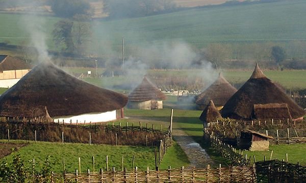 Butser ancient farm with smoky chimneys and green hills