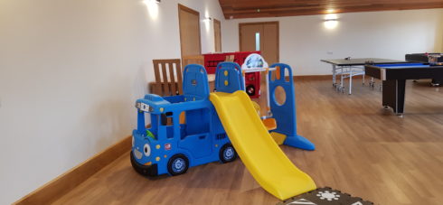 Adventure plastic bus with a yellow slide on a wooden floor