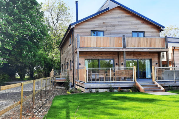 Rear view of Scots Pine holiday accommodation at Wallops Wood with grassy garden and large decking area