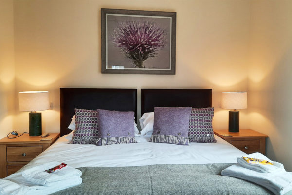 Beautiful bedroom decorated in warm heather and pale grey tones in Scots Pine holiday accommodation