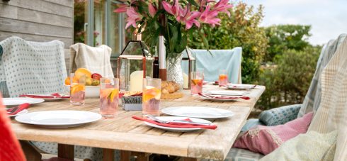 Early Mist patio table laid for outdoor dining with flowers and glasses of Pimms on the table in the garden of this luxury holiday cottage