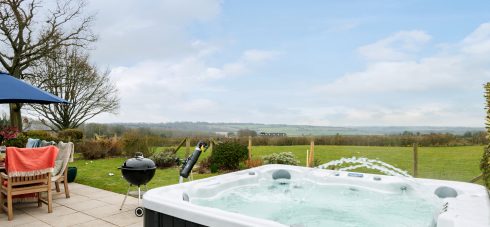 Garden with hot tub and view across the lawned meadow, and the surrounding countryside, from luxury holiday cottage Early Mist, one of our self catering holiday cottages