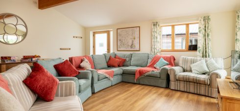 Seating area in large self catering cottage Silver Birch, decorated in teal, cream and terracotta colours, wooden floor, and lots of windows. Ample room to seat 16 people as part of Silver Mist holiday cottage which sleeps 16